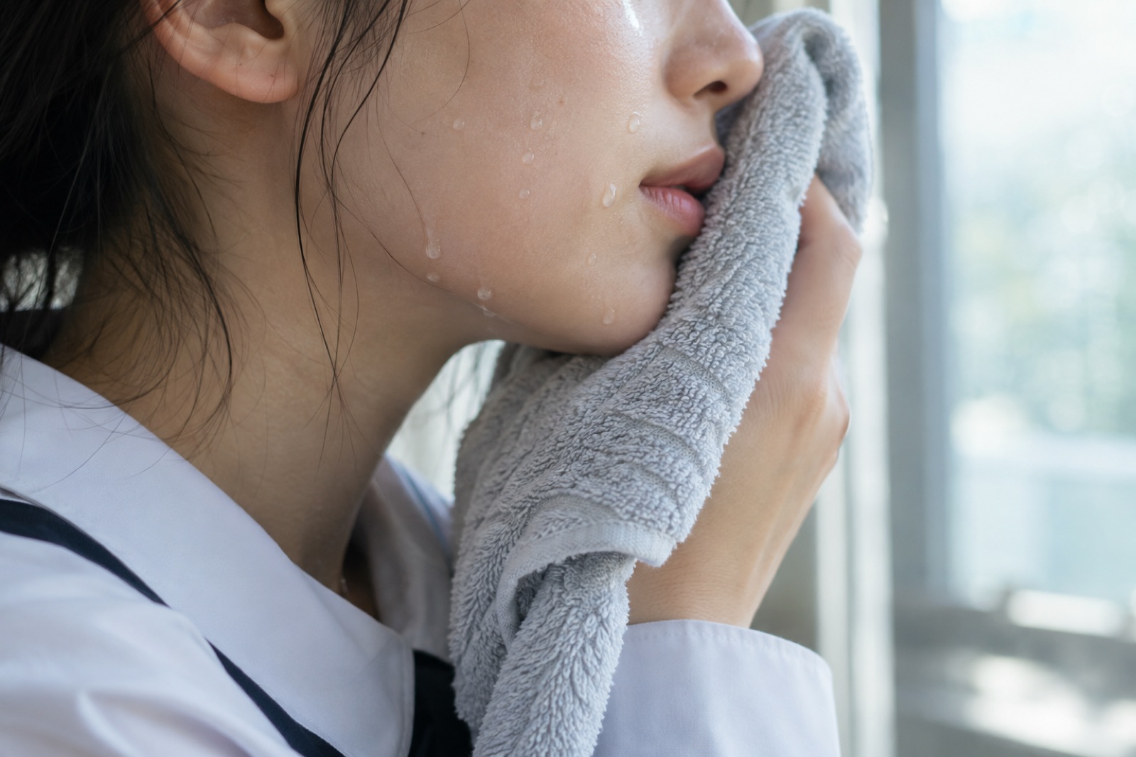 교복 소매가 보이는 손으로 볼에 수건을 살짝 눌러 대는 옆모습